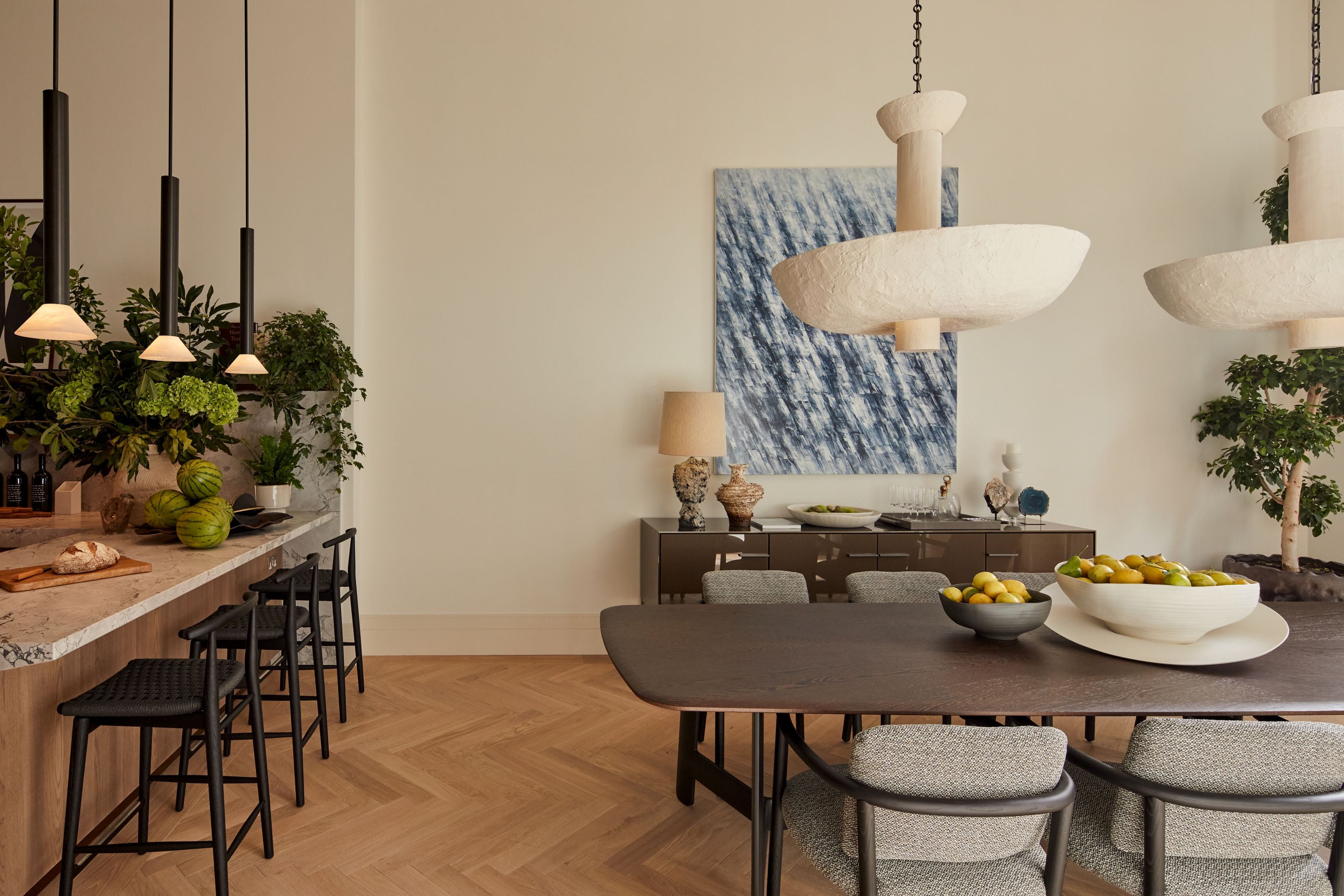 Modern dining room with a long table, chairs, and decorative elements.