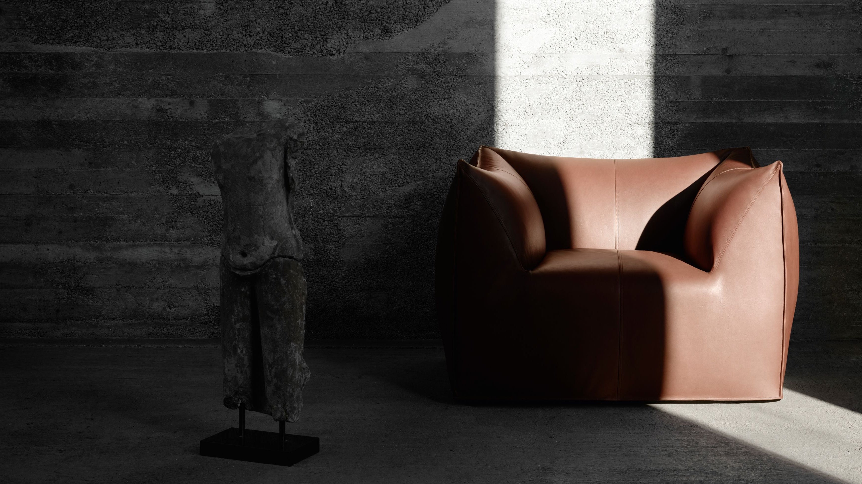 Brown leather armchair in a dimly lit room with a textured wall.