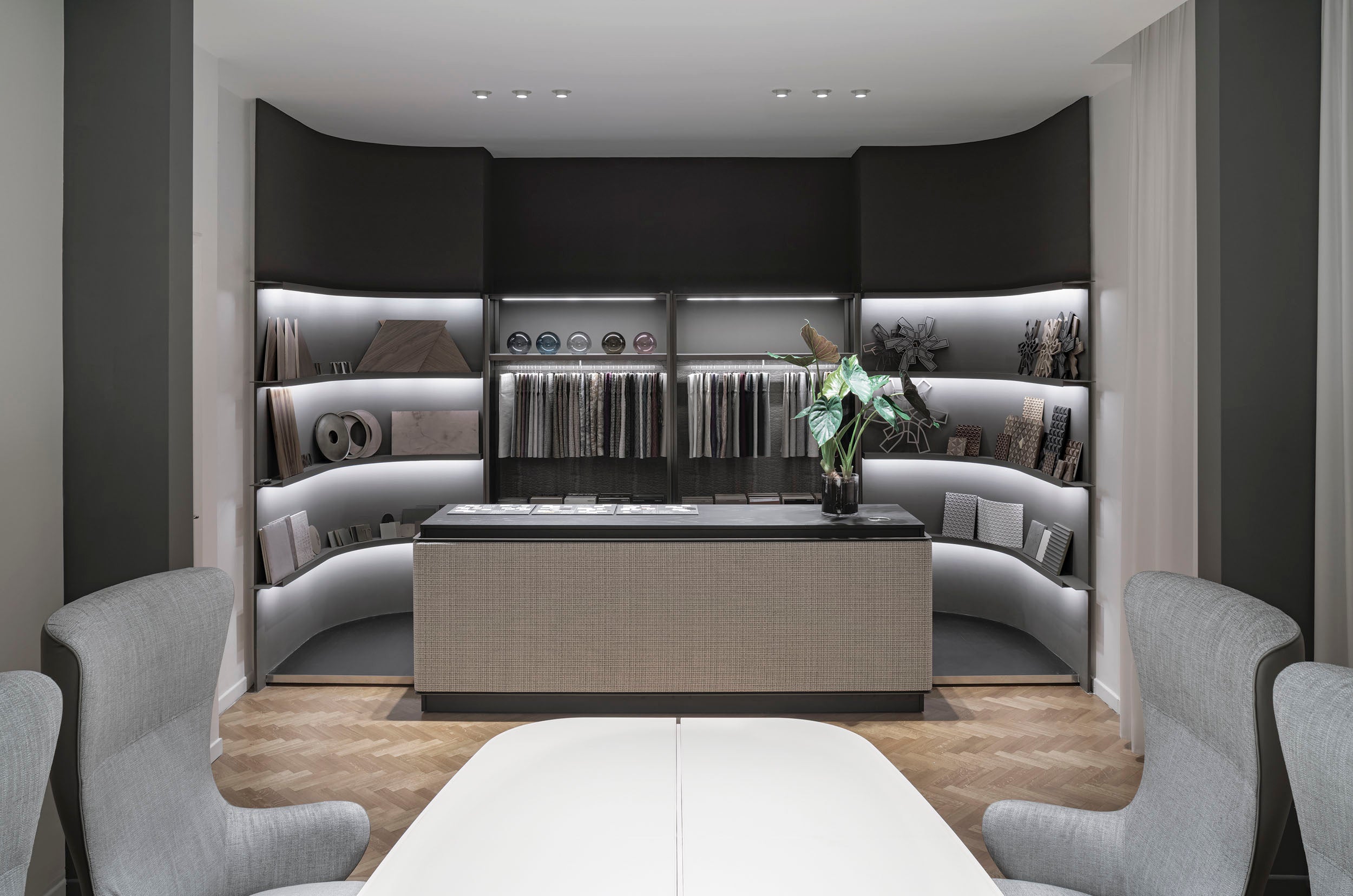 Modern interior design with gray chairs, a white table, and a dark wall with shelves.