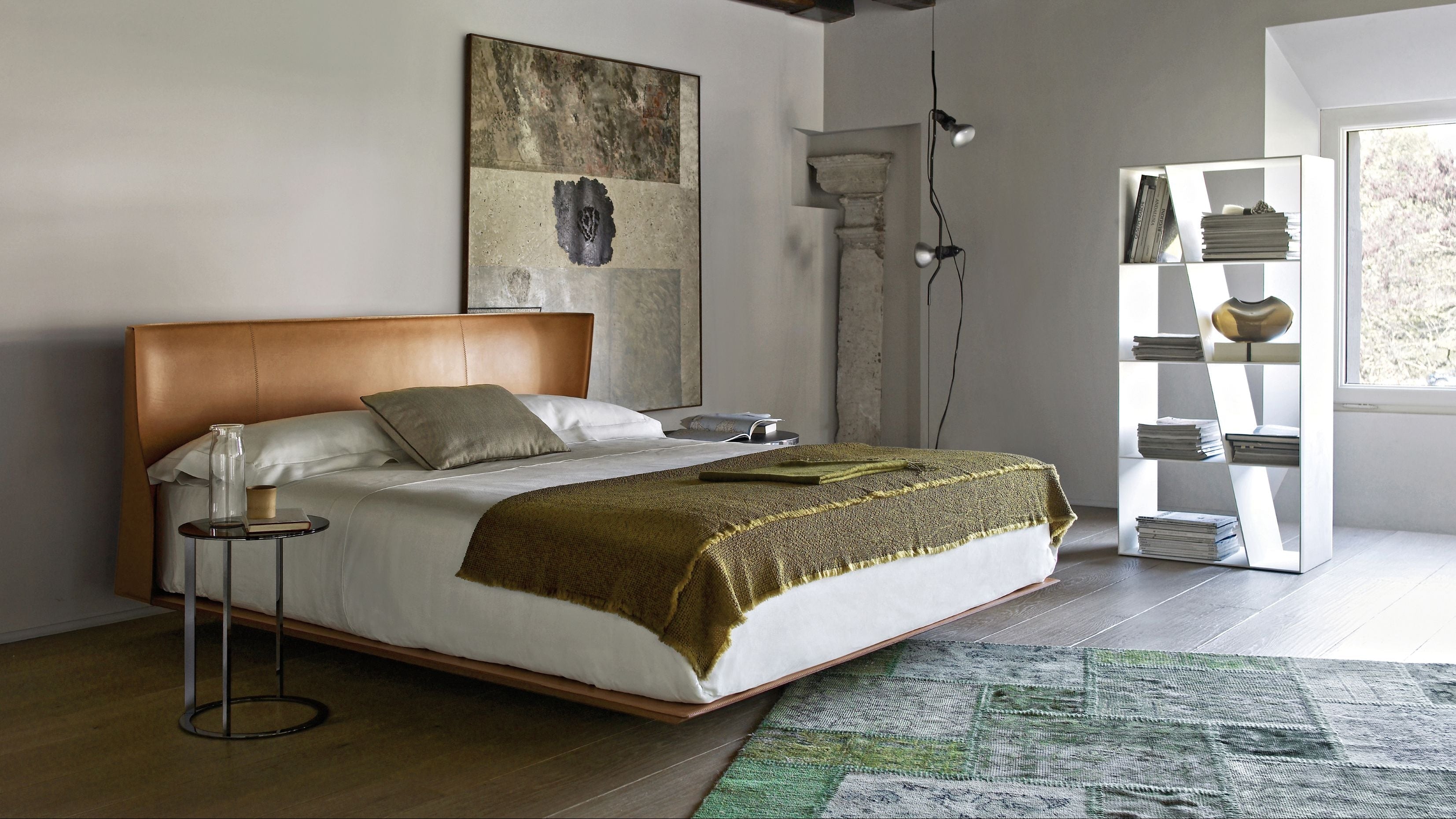 Modern bedroom with a bed, side table, and artwork on the wall.