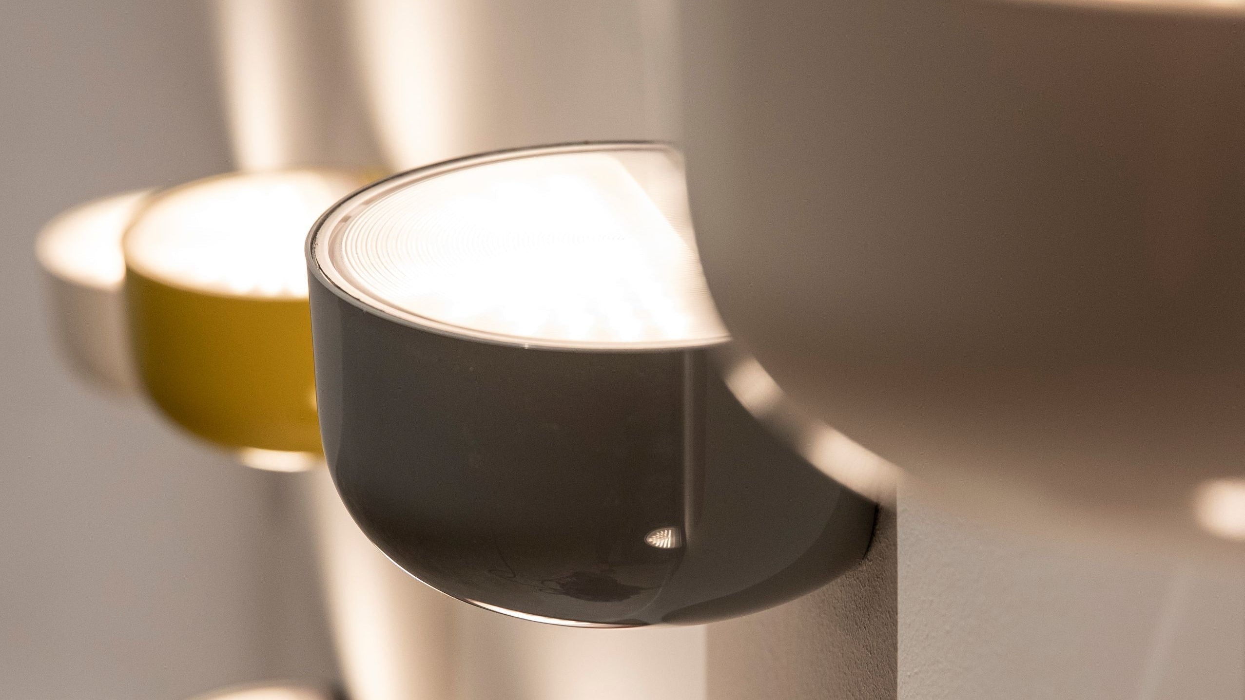 Close-up of modern wall-mounted lights with different finishes on a neutral background