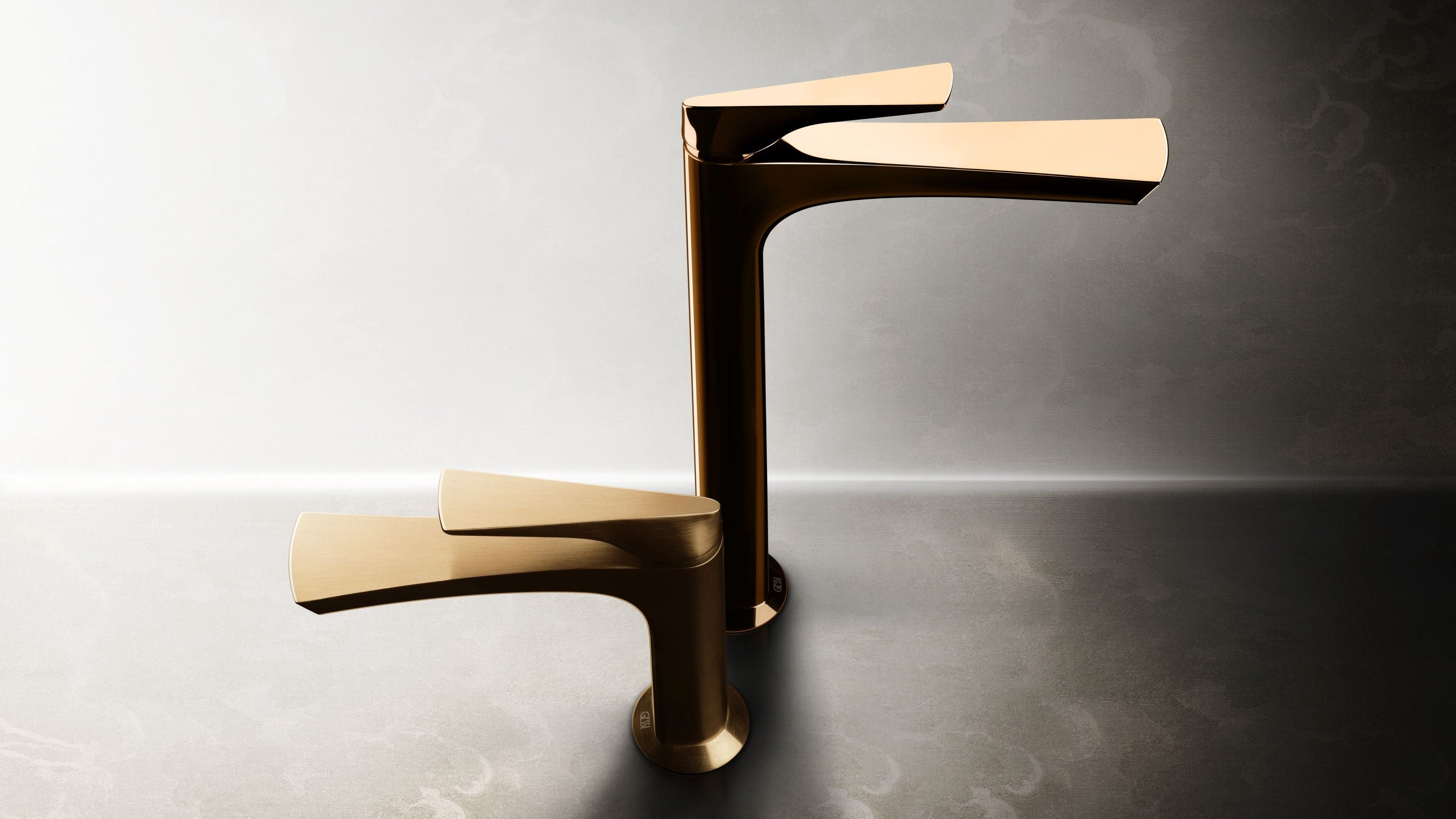 Pair of gold faucets on a textured surface with a gradient background