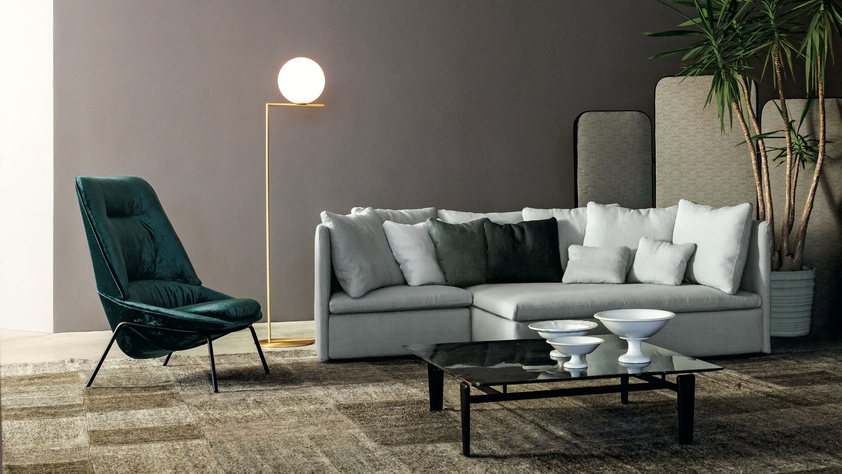 Modern living room with a gray sectional sofa, green armchair, and decorative items.