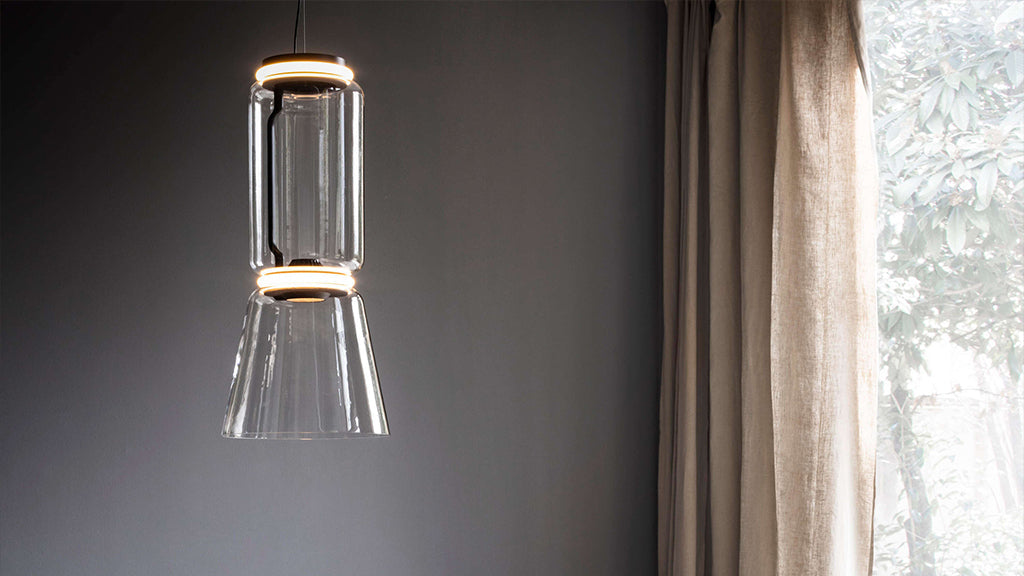 Modern pendant light hanging against a gray wall with a window in the background