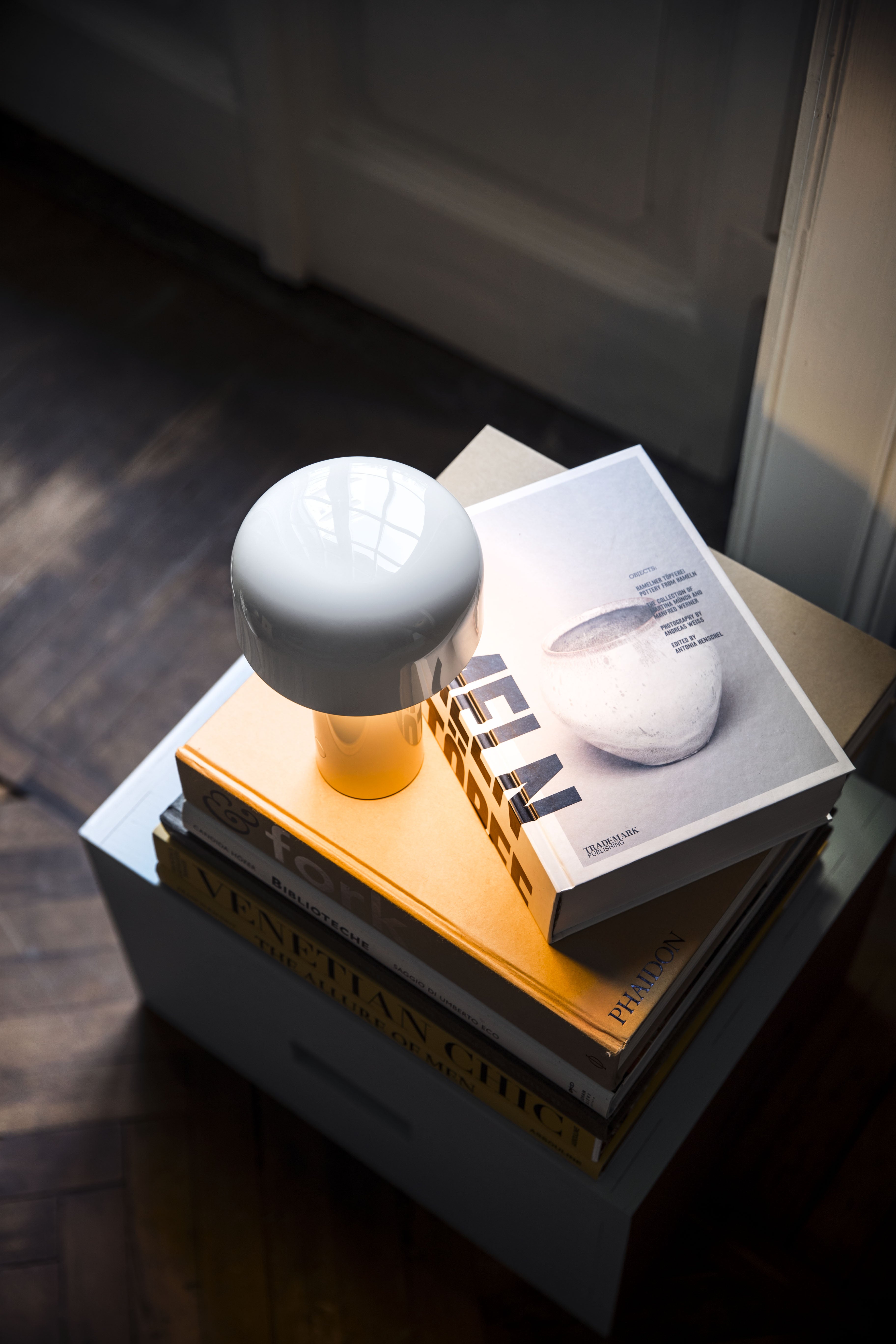 White lampshade on a stack of books with a blurred background