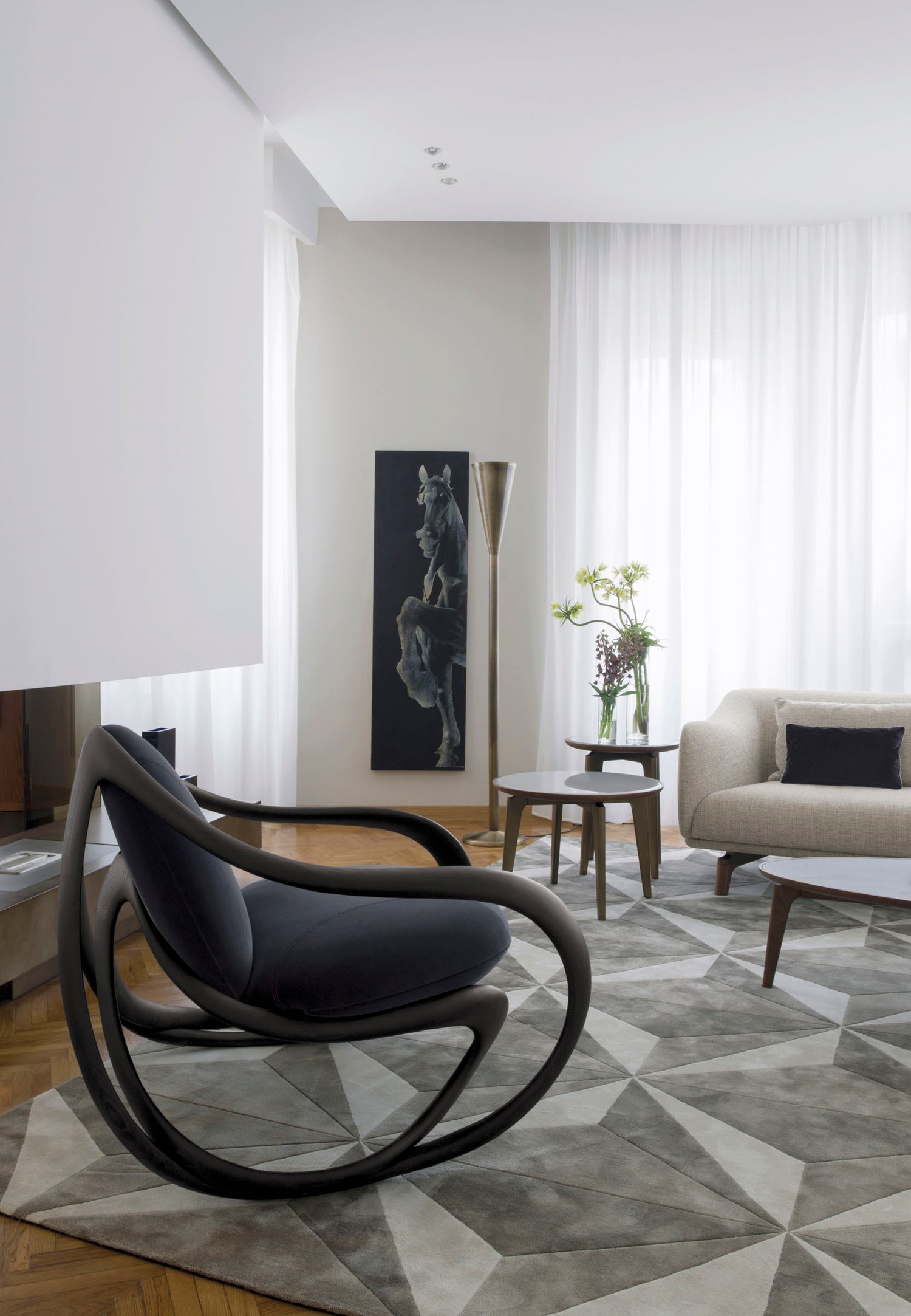 Modern living room with a gray armchair, sofa, and abstract art on the wall.